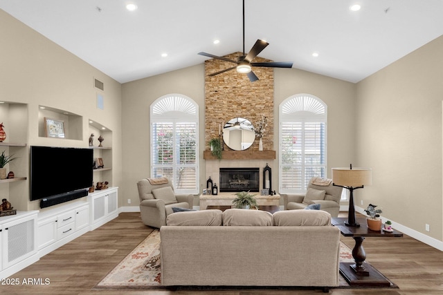 living area with wood finished floors, a healthy amount of sunlight, visible vents, and a large fireplace