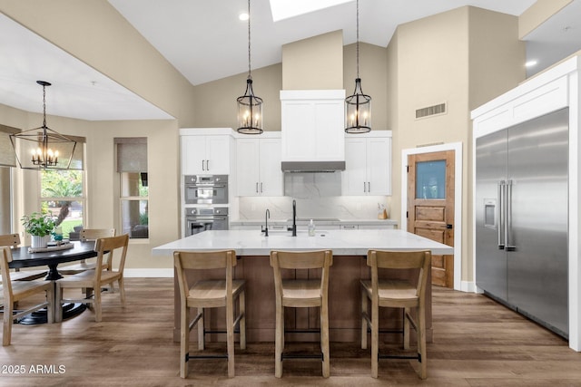 kitchen featuring visible vents, dark wood finished floors, a sink, stainless steel appliances, and backsplash