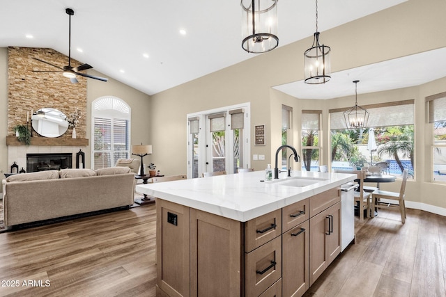 kitchen featuring pendant lighting, a large fireplace, light wood-style floors, and a sink