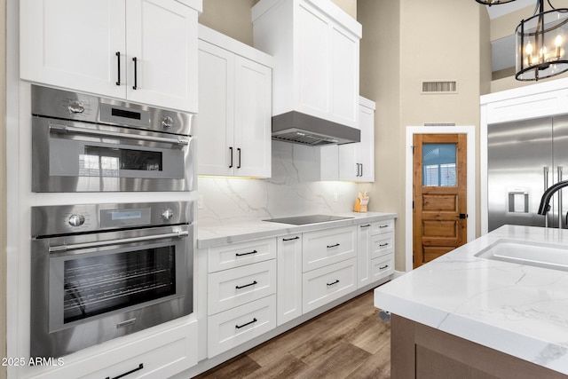 kitchen with visible vents, a sink, white cabinets, appliances with stainless steel finishes, and tasteful backsplash