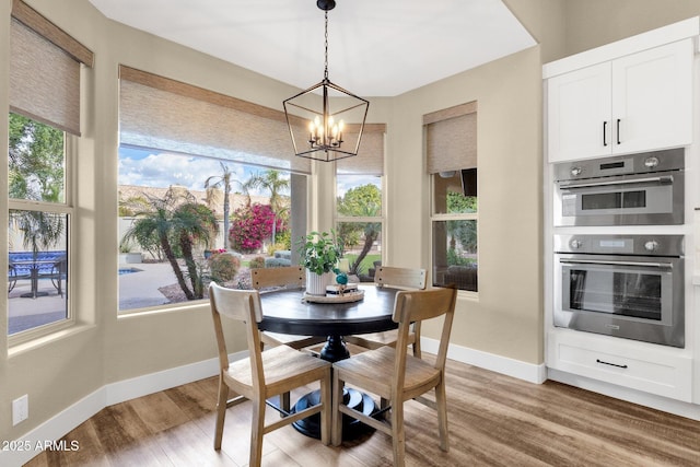 dining room featuring an inviting chandelier, light wood-style flooring, and baseboards