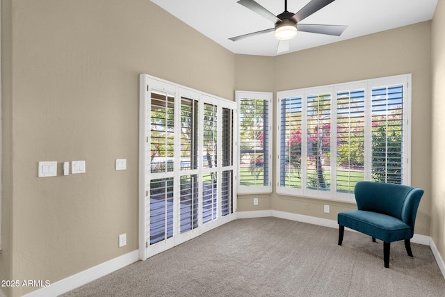 living area featuring baseboards, carpet floors, a healthy amount of sunlight, and a ceiling fan