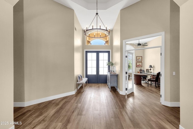 entryway with dark wood finished floors, a chandelier, french doors, and baseboards