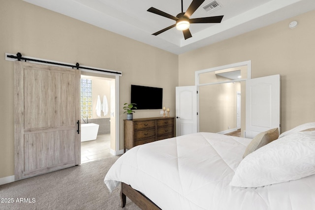 bedroom featuring visible vents, a barn door, connected bathroom, a raised ceiling, and light colored carpet