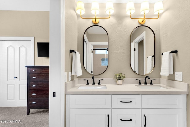 full bath featuring a sink, double vanity, and a textured wall