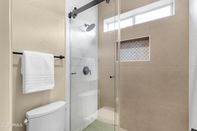 full bath with a stall shower, toilet, and a textured wall