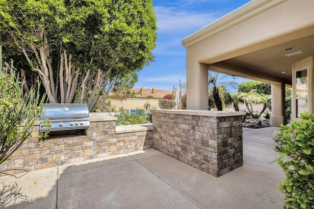 view of patio / terrace featuring a grill, an outdoor kitchen, and fence