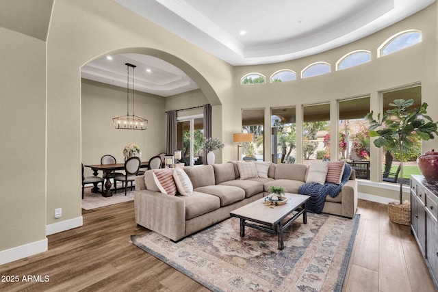 living room featuring baseboards, a high ceiling, a tray ceiling, and wood finished floors