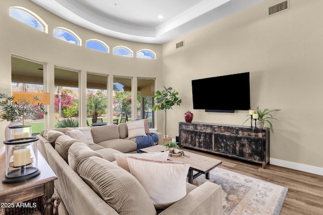 living area with visible vents, a healthy amount of sunlight, baseboards, and wood finished floors