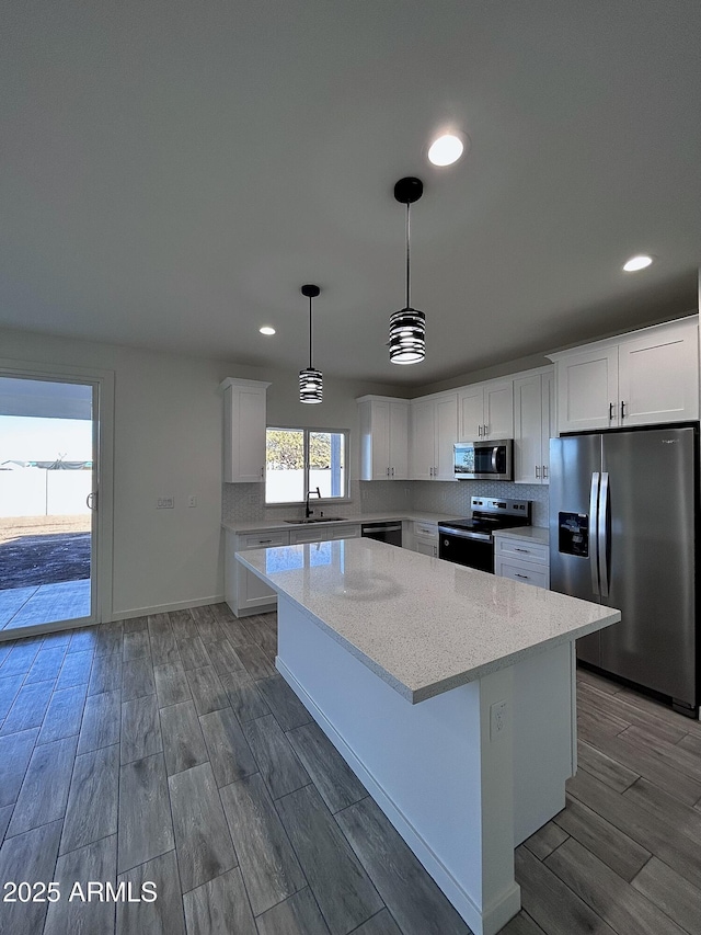 kitchen with white cabinets, stainless steel appliances, light stone counters, and hanging light fixtures