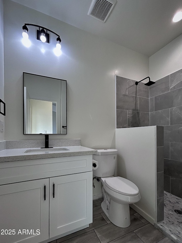 bathroom featuring tiled shower, vanity, and toilet