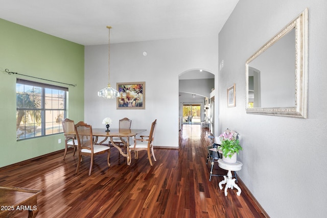 dining room featuring a towering ceiling and dark hardwood / wood-style flooring