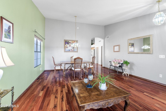 living room featuring an inviting chandelier, dark hardwood / wood-style floors, and vaulted ceiling