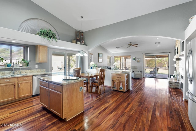 kitchen with vaulted ceiling, a kitchen island, sink, stainless steel dishwasher, and light stone countertops