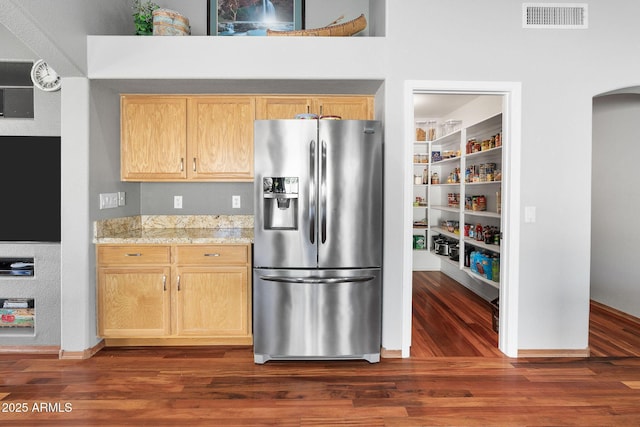 kitchen with stainless steel refrigerator with ice dispenser, dark hardwood / wood-style flooring, light stone countertops, and light brown cabinets