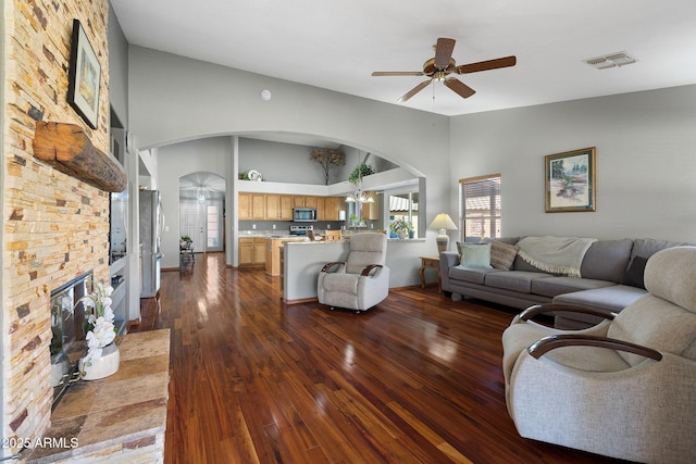 living room featuring lofted ceiling, dark wood-type flooring, a fireplace, and ceiling fan