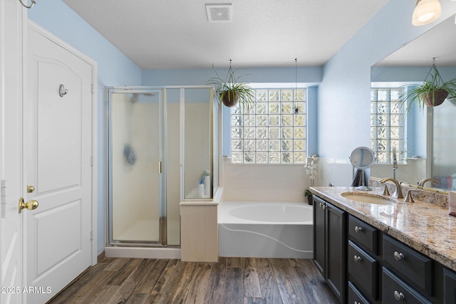 bathroom featuring vanity, hardwood / wood-style flooring, independent shower and bath, and a textured ceiling