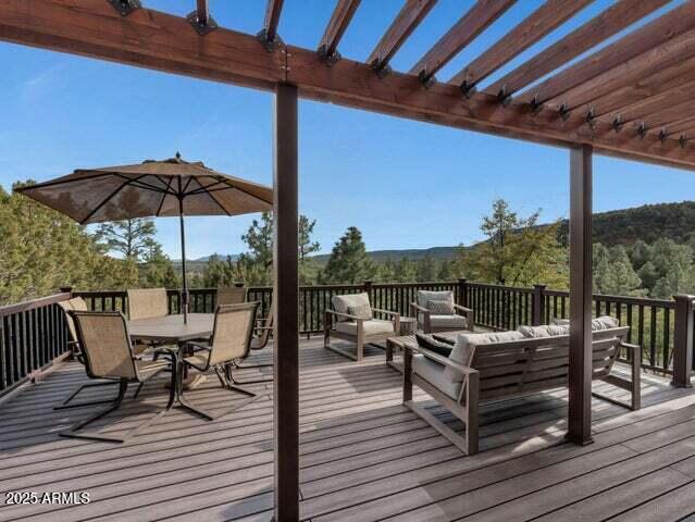 wooden deck with outdoor dining area, a pergola, and an outdoor living space