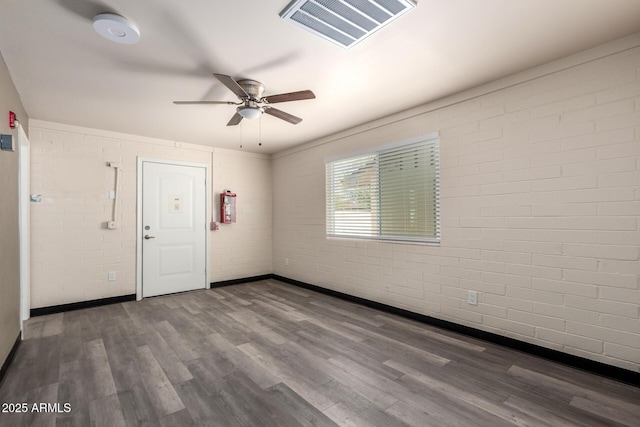 spare room with ceiling fan, brick wall, wood finished floors, and visible vents