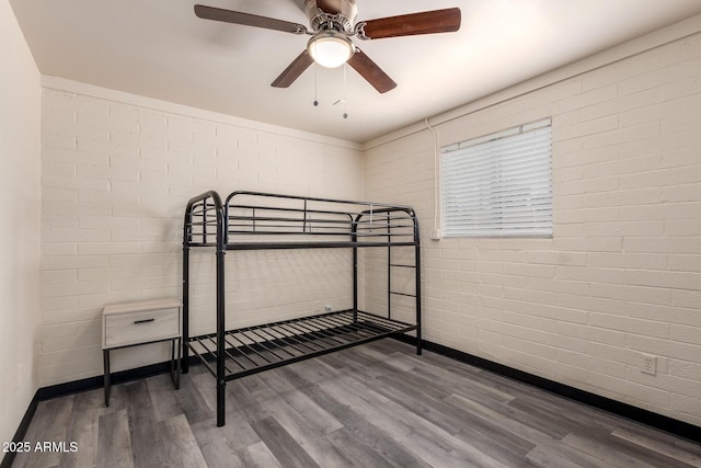 bedroom with brick wall, a ceiling fan, and wood finished floors