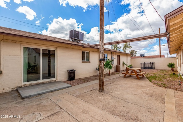 back of property with a patio, central AC unit, brick siding, fence, and outdoor dining space