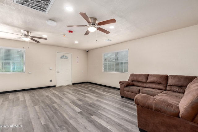 living area featuring visible vents, ceiling fan, baseboards, and wood finished floors