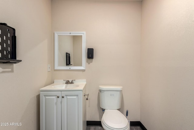 bathroom with toilet, vanity, and baseboards