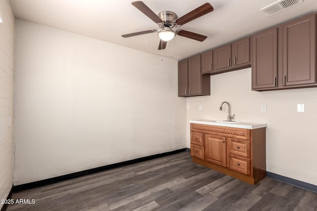 kitchen with dark wood-type flooring, a sink, visible vents, baseboards, and light countertops