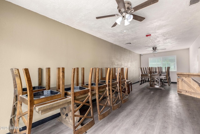 misc room featuring a textured ceiling, wood finished floors, visible vents, and a ceiling fan