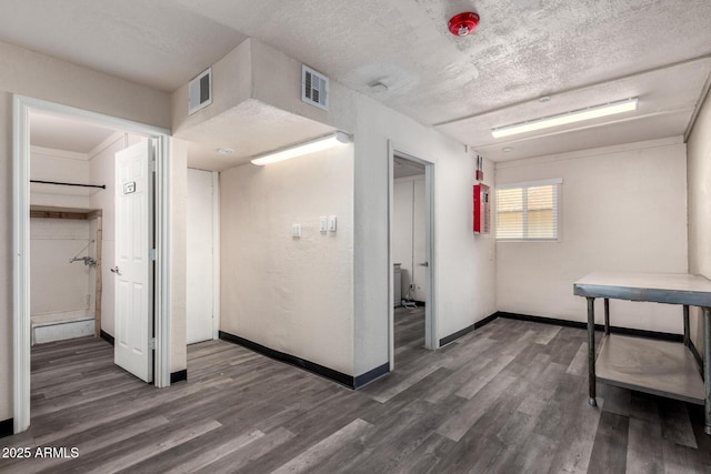 interior space featuring a textured ceiling, visible vents, and wood finished floors