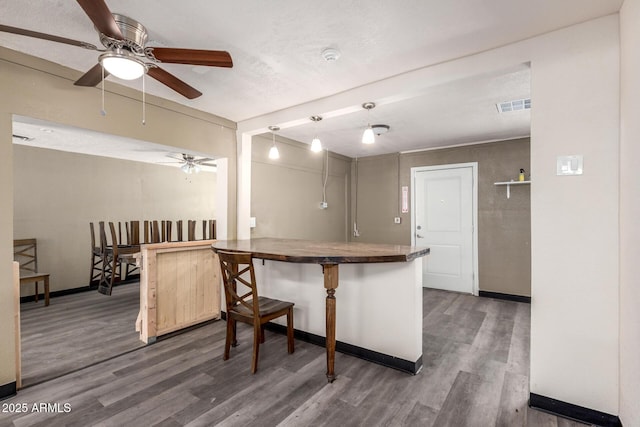 kitchen with a peninsula, wood finished floors, visible vents, and baseboards