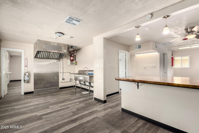 kitchen featuring dark wood-style floors, wood counters, visible vents, and a textured ceiling