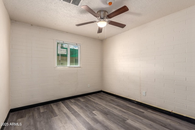 spare room featuring visible vents, baseboards, a ceiling fan, dark wood-style floors, and a textured ceiling