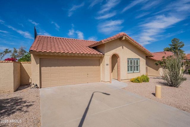mediterranean / spanish house featuring driveway, stucco siding, an attached garage, and fence