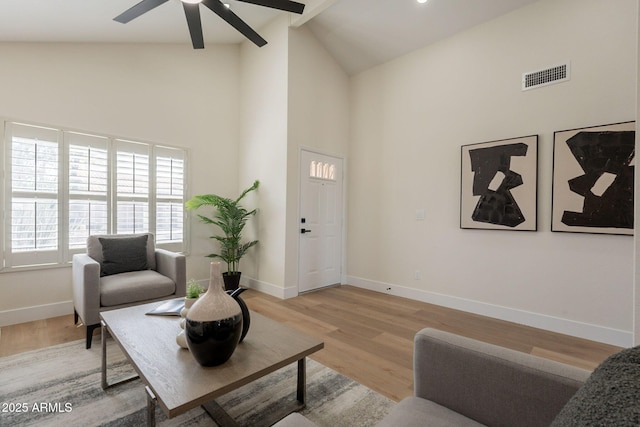 living room featuring a ceiling fan, baseboards, visible vents, high vaulted ceiling, and light wood-style floors