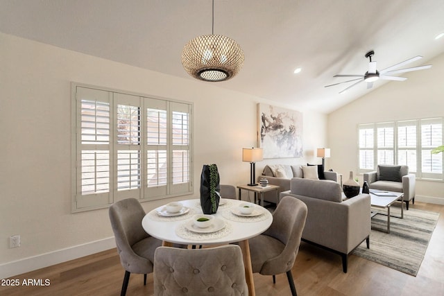 dining room featuring lofted ceiling, baseboards, light wood-type flooring, and a ceiling fan