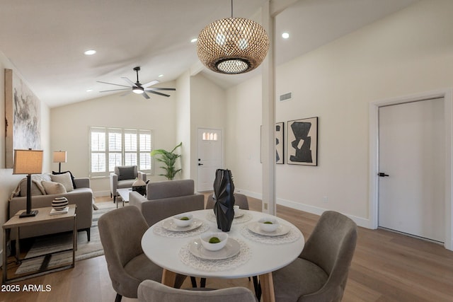 dining area with baseboards, high vaulted ceiling, ceiling fan, and wood finished floors