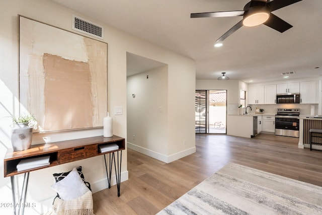 interior space featuring recessed lighting, baseboards, light wood finished floors, ceiling fan, and visible vents