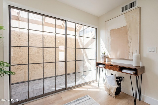 doorway featuring baseboards, visible vents, and wood finished floors