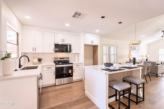 kitchen featuring a breakfast bar area, light wood finished floors, visible vents, a sink, and appliances with stainless steel finishes