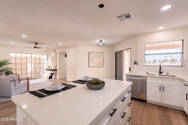 kitchen featuring dishwasher, visible vents, a sink, stovetop, and light wood-style floors
