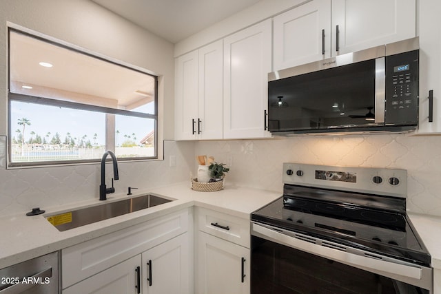 kitchen featuring white cabinetry, stainless steel appliances, decorative backsplash, and a sink