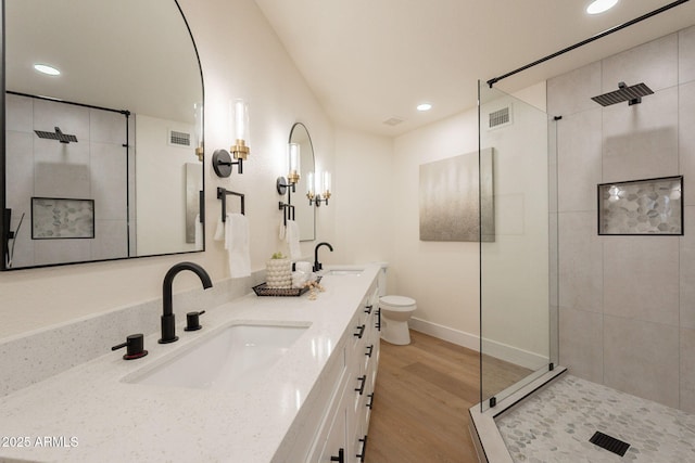 full bath featuring tiled shower, visible vents, a sink, and wood finished floors