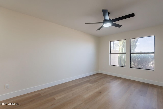 spare room featuring baseboards, light wood finished floors, and ceiling fan