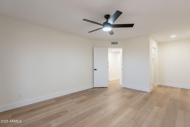 spare room with light wood-type flooring, visible vents, baseboards, and a ceiling fan