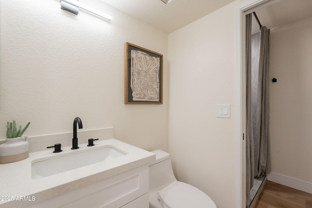 bathroom with toilet, wood finished floors, and vanity