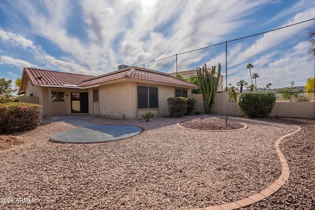 back of property with stucco siding, a tile roof, fence, and a patio area