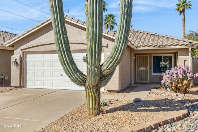 view of front facade with concrete driveway, an attached garage, a tile roof, and stucco siding