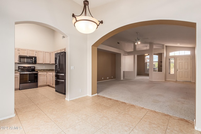 interior space featuring black appliances, light brown cabinetry, hanging light fixtures, light carpet, and lofted ceiling