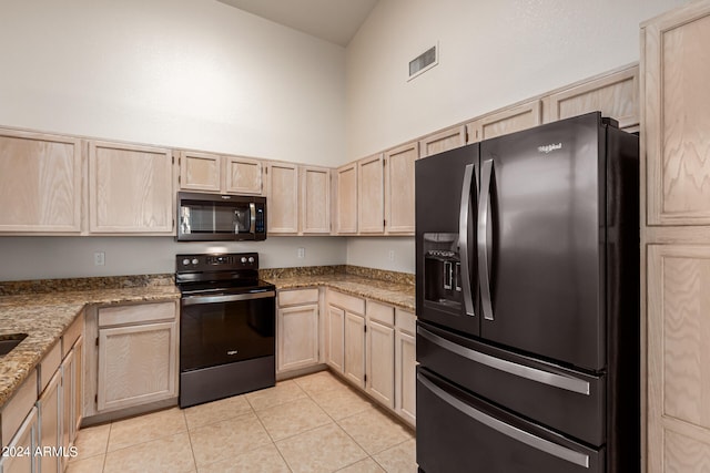 kitchen with light brown cabinets, black appliances, light stone countertops, light tile patterned floors, and high vaulted ceiling